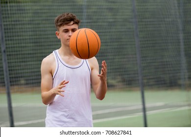Teenage boy tossing a basketball from one hand to another on a court