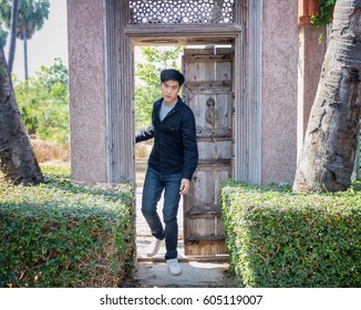 A Teenage Boy Is Walking Through The Wooden Door.