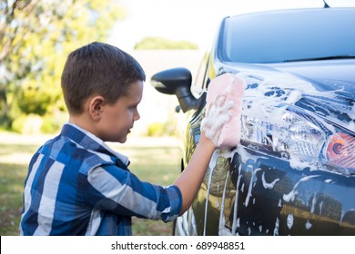 Teenage boy washing a car on a sunny day - Powered by Shutterstock