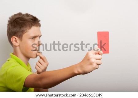 a teenage boy with whistle and red card looks like a sports coach or referee