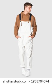 Teenage boy in white dungarees and brown hoodie streetwear photoshoot