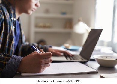 Teenage boy working at a desk in his bedroom, close up
