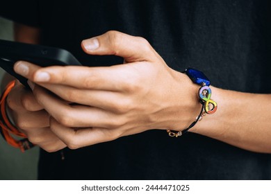 Teenage boy with wristlet with autism infinity rainbow symbol sign on his hand. World autism awareness day, autism rights movement, neurodiversity, autistic acceptance movement - Powered by Shutterstock