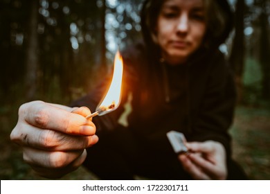 Teenage bully in hood holds burning match in his hand. Forest arsonist. Fire danger. Concept of arson and flame in night - Powered by Shutterstock