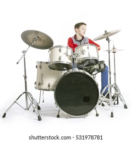 teenage caucasian boy plays drums in studio with white background