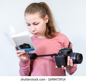 Teenage Caucasian Girl Reading User Manual Of DSLR Camera, Learning Photography, A Grey Background