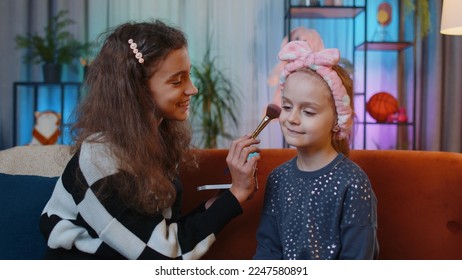 Teenage child helps or teaches to do face makeup her little sister kid girls. Female siblings children best friends putting applying make-up cosmetic at home play room. Friendship, family relationship - Powered by Shutterstock