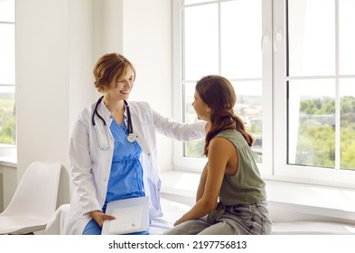 Teenage child visits friendly doctor. Cheerful, positive pediatrician in white coat smiles and puts her hand on shoulder of happy school girl. Healthcare, medical checkup, trust, and support concept - Powered by Shutterstock