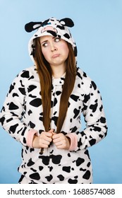 Teenage confused girl in funny nightclothes, pajamas cartoon style making silly face, woman in doubt, studio shot on blue.