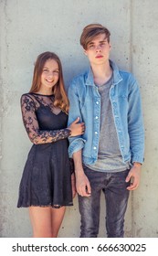 Teenage Couple Feeling In Love, Girl Holding Boy Tenderly Boy Standing Shy Over Urban Background, Filter Adds Warm Light To Photo