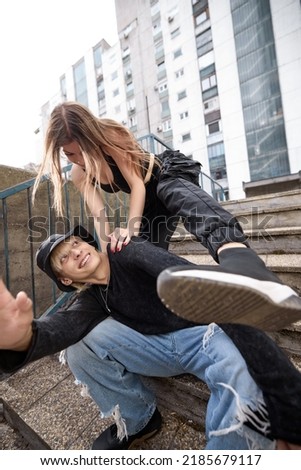 A teenage couple is having fun in the urban exterior and acting silly.