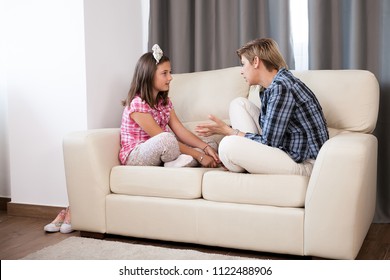 Teenage daughter and her mother on the sofa in the living room talking