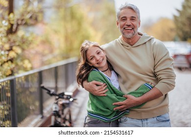 Teenage daughter hugging her father outside in town when spenidng time together. - Powered by Shutterstock