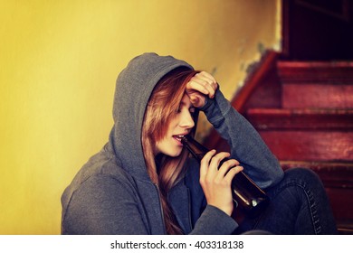 Teenage Depressed Woman Sitting On The Staircase And Drinking A Beer