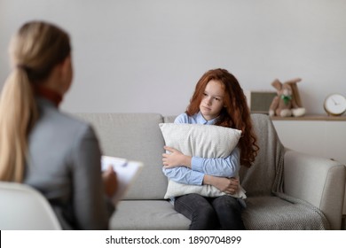 Teenage Depression Concept. Female child psychologist working with sad girl in office or at home, stressed teenager talking about family problems, feeling anxiety, sitting on sofa, hugging pillow