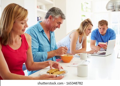 Teenage Family Having Breakfast In Kitchen With Laptop