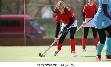 Teenage female field hockey player in attack with the ball. Young girl with he ball at field hockey game