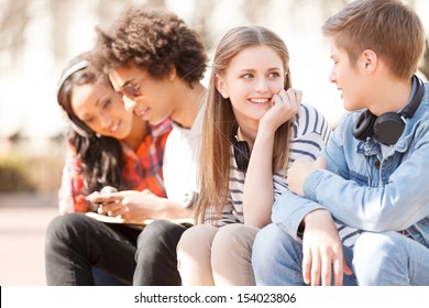 Teenage friends. Four cheerful teenage friends talking to each other