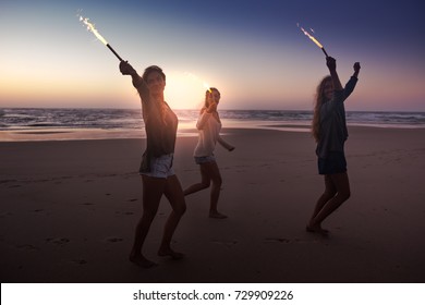 Teenage Friends Running On A Beach With Fireworks