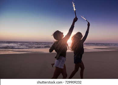 Teenage Friends Running On A Beach With Fireworks