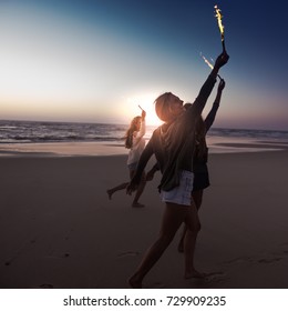 Teenage Friends Running On A Beach With Fireworks