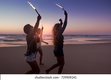 Teenage Friends Running On A Beach With Fireworks