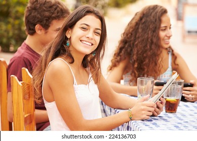 Teenage Friends Sitting At CafÃ?Â¢?? Using Digital Devices - Powered by Shutterstock