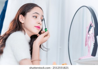 Teenage girl applying makeup, young girl putting some mascara on her eyelashes in front of a mirror
 - Powered by Shutterstock