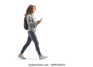 Teenage girl with a backpack walking and typing on a mobile phone isolated on white background - Shutterstock ID 1909103923