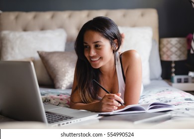 Teenage girl in bedroom using laptop