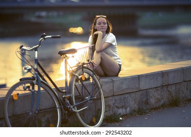 Teenage Girl With The Bike, Sitting On The Promenade During Sunset. Cross Process Film Style.