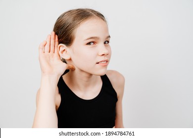 A Teenage Girl In A Black T-shirt Holds Her Hand By Her Ear And Listens. Secret Sales In Stores Only For A Select Few. Shopping. School Secrets.