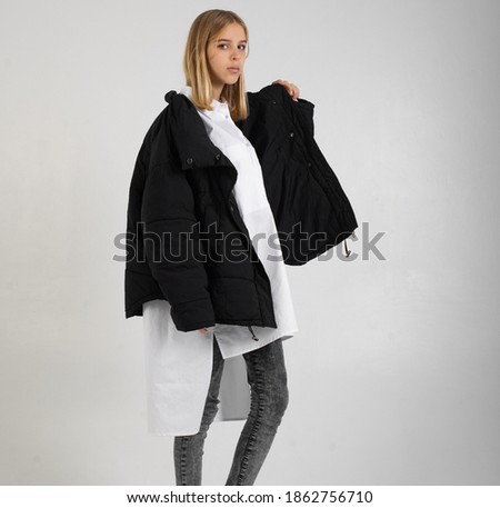 teenage girl with blond hair in a black oversized jacket worn over a white long shirt