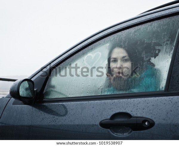 Teenage girl blowing kiss from\
car