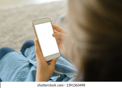 Teenage Girl In A Blue Dress Sitting On An Armchair While Holding A Smart Phone With A Blank Screen In The Hands. Young Girl Using Scrolling On Social Media, Youth Addiction