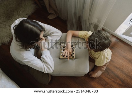 Similar – child girl playing checkers with her dad at home