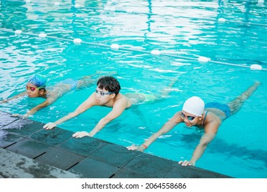 Teenage Girl And Boy In Swimsuits And Swimming Trunks Wearing Swimming Goggles While Wave Maker Movement Together