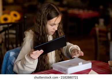 A Teenage Girl In A Cafe. She Unpackes A New Gadget. Generation Z. Good Thing. Online Communication. Shopping. Outside The Home.