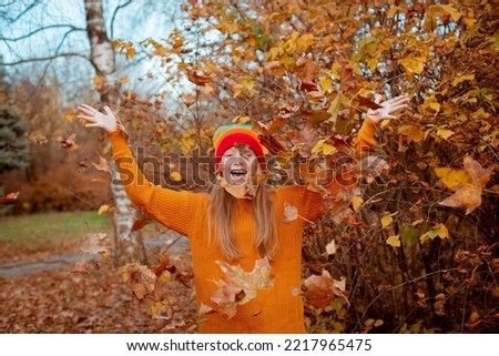 teenage girl catches falling autumn leaves in autumn in the park, happy