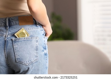 Teenage girl with condom in pocket of her jeans indoors, closeup.