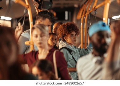 Teenage girl with curly hair standing on a crowded public bus among other passengers. - Powered by Shutterstock