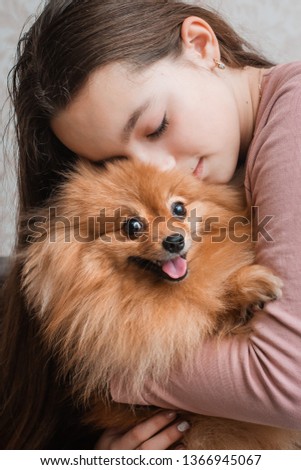 Teenage girl with a dog breed Spitz rejoices with a pet at home on the floor. Care and training of a pet. Content Fluffy puppy. To groom long-haired Pomeranian. Orange red Stock photo © 