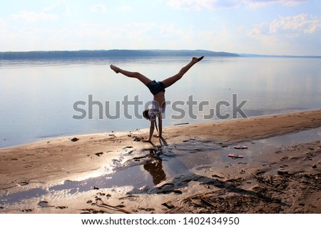 Teenage girl doing gymnastics on the river Bank. Sports summer classes.
