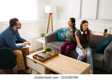 Teenage Girl With Dyed Hair Taking A Selfie During A Therapy Session With Her Mom And A Male Psychologist