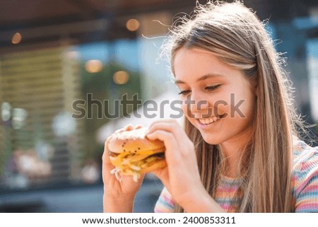 Teenage girl eating french fries and fooling around in an outside restaurant