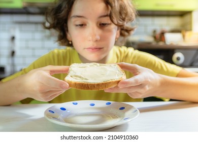 Teenage girl eating snack of toaster bread with cheese or butter. bite toasted toast bread. want to eat buttered toaster bread. young woman looks at toaster bread spread with melted cheese  - Shutterstock ID 2104910360