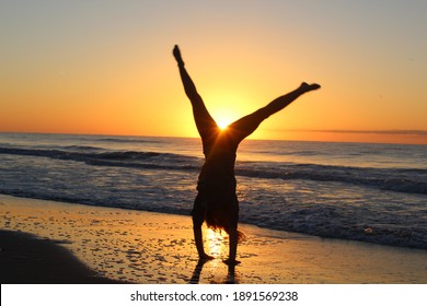 Teenage Girl Happy Doing Cartwheel On Beach In Summer