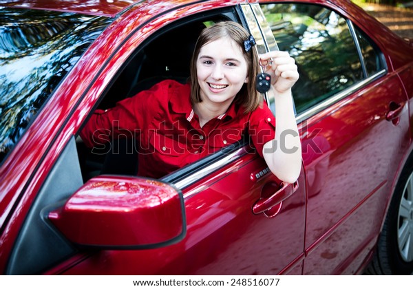 Teenage girl with her driver\'s license driving a new car\
and holding keys.  