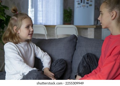 A teenage girl and her sister look at each other, share secrets and mysteries. The concept of warm relationships, love, trust and understanding in the family. - Shutterstock ID 2255309949