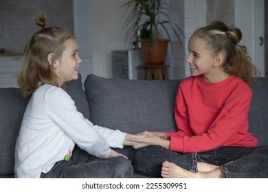 A teenage girl and her sister look at each other and talk while sitting at home. The concept of trusting relationships and help in solving the problem, understanding and friendship - Shutterstock ID 2255309951